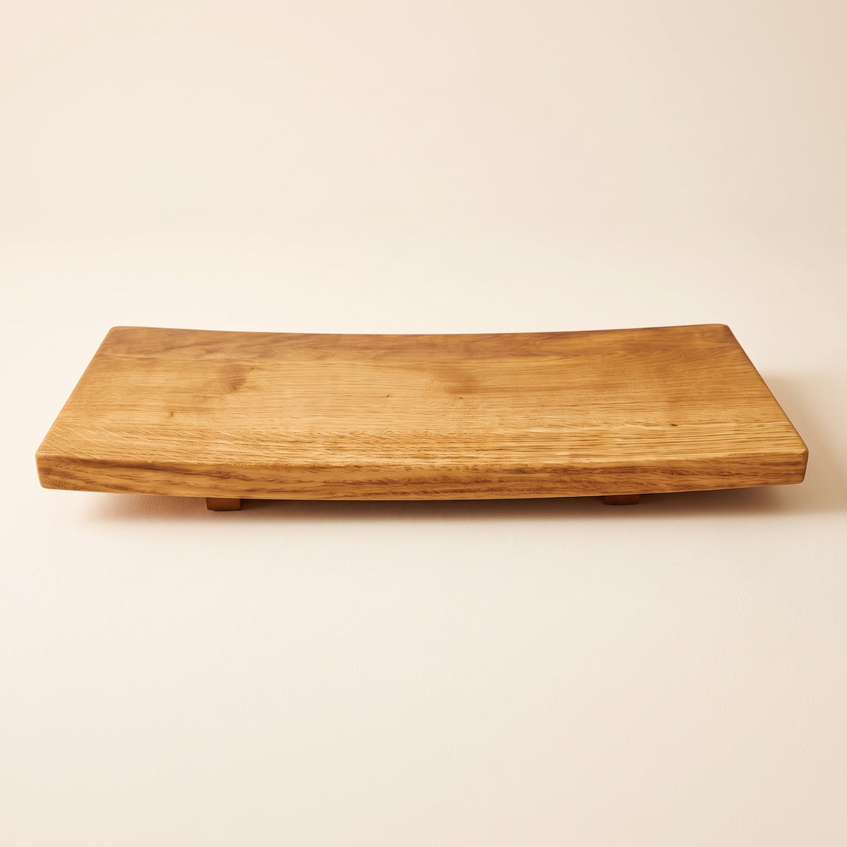 A rectangular wooden serving board with a natural live edge and small feet, shown on a plain beige background.