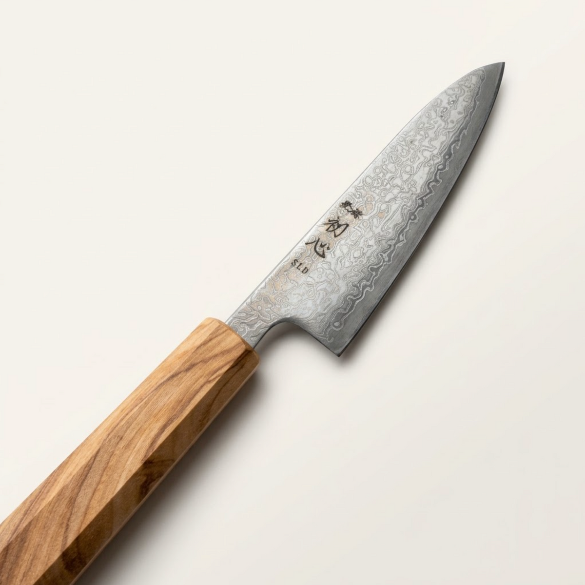 Macro view of Hatsukokoro Hikari kurosome etched black damascus pattern and SLD steel cutting edge
