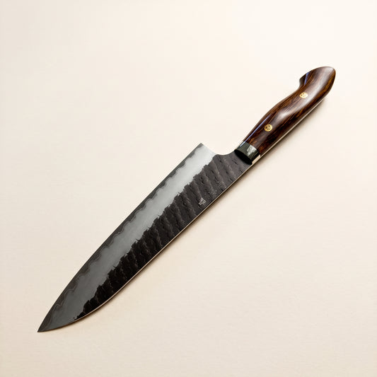 Nigara SG2 Kurouchi Hexagonal Tsuchime Gyuto 210mm with Western full-tang desert ironwood handle on dark background