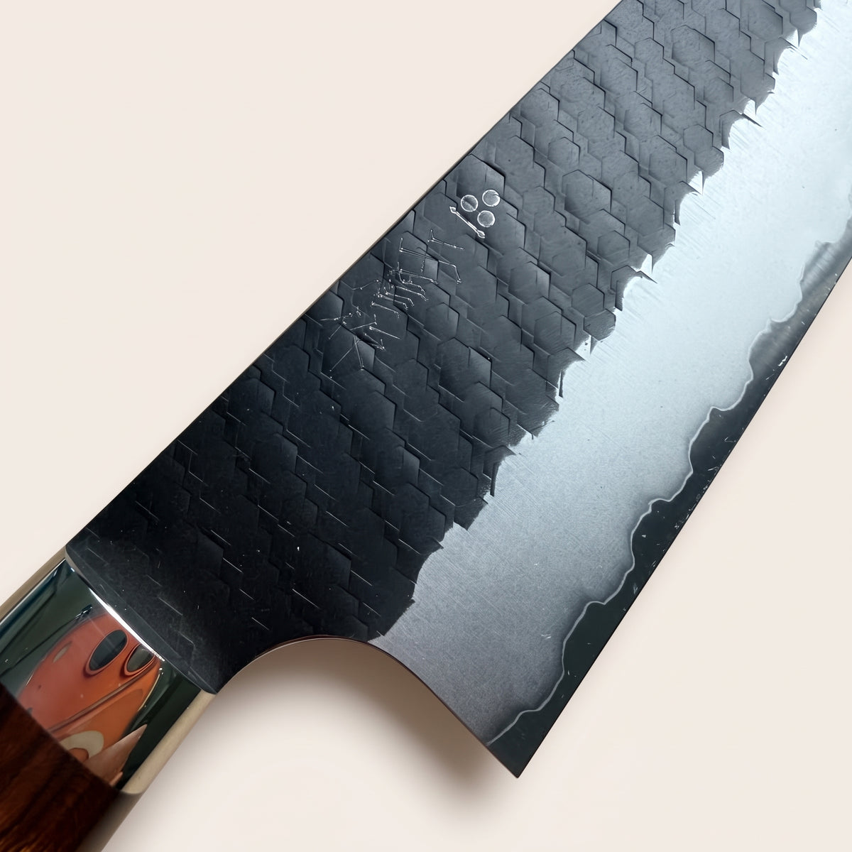 Close-up view of Nigara hand-hammered hexagonal tsuchime texture, raw kurouchi finish, and SG2 steel core edge